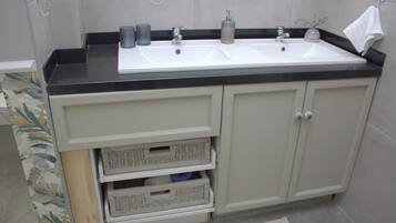 A bathroom with a double sink, two drawers, and a towel rack.