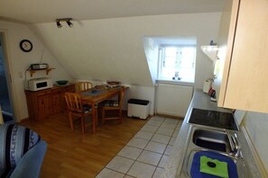 Une cuisine de taille réduite comprenant une table à manger, des chaises, un four à micro-ondes et une fenêtre.