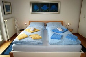Una cama doble con dos almohadas, una mesita de noche con lámpara y una obra de arte enmarcada en la pared.