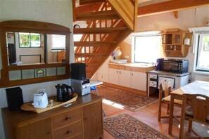 Eine kompakte Küche mit Holzschränken, einer Mikrowelle und einer Kaffeemaschine.