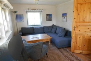 Ein Zimmer mit einer Couch, einem Tisch, einem Stuhl, einem Fenster und einer Tür.