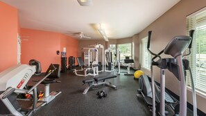 Un gimnasio con equipo de ejercicio, dispensador de agua y ventilador de techo.