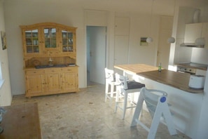 Eine Küche mit Holzschränken, einer Holzausziehtheke und weißen Stühlen.