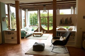 A spacious living area with large windows, a sofa, a chair, and a coffee table. - Wyk's Captain's House (Wyk auf Föhr)