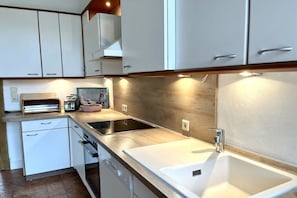 A modern kitchen with white cabinetry, a built-in oven, and a stainless steel sink. - Wyk's Captain's House (Wyk auf Föhr)