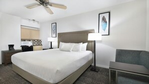 A hotel room with a bed, bedside lamps, a desk, a chair, a ceiling fan, and artwork on the walls. - Scottsdale Studio Hotel at WorldMark – Pools, Golf & Desert Views (Scottsdale)
