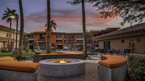 A courtyard with outdoor seating, a fire pit, palm trees, and a building with multiple floors and balconies. - Scottsdale Studio Hotel at WorldMark – Pools, Golf & Desert Views (Scottsdale)