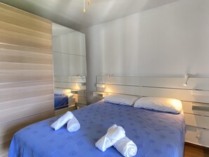 A hotel room with a bed, a nightstand, a mirror, and a wall with a wooden panel design. - Villa in Nerja Near Burriana Beach (Nerja)
