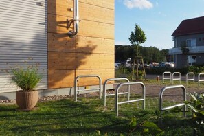 A building with a wooden facade, metal railings, and a grassy area with a potted plant. - Apartment in Plau am See with swimming pool (Plau am See)