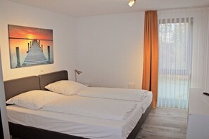 A hotel room with a bed, a desk, a lamp, a painting, and a window with curtains. - Apartment in Plau am See with swimming pool (Plau am See)