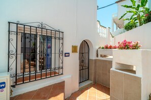 A narrow alleyway with a metal gate, a tiled floor, and a white wall with a small blue plaque. - Two-bedroom Villa Near the Beach (Nerja)