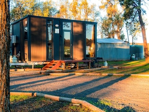 Una cabaña moderna con fachada de madera, puerta corrediza de vidrio y un pequeño porche.