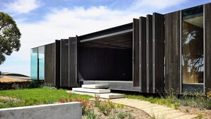 Un edificio moderno con techo plano, amplios ventanales de vidrio y fachada de madera.
