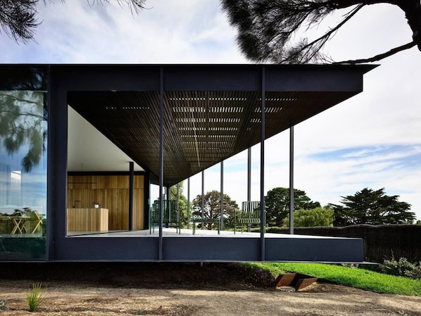 A modern building with a large glass facade, a wooden interior, and a metal roof structure.