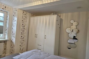 A bedroom with a bed, wardrobe, and wall-mounted mirrors. - Holiday apartment with 1 bedroom (Wyk auf Föhr)