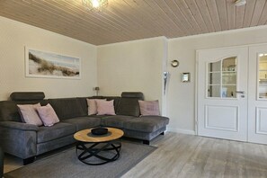 A living room with a sectional sofa, a coffee table, and a painting on the wall. - Holiday apartment with 1 bedroom (Wyk auf Föhr)