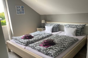 Una cama doble con ropa de cama estampada, una mesita de noche con lámpara y una pequeña decoración en la pared.
