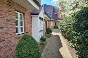 A brick house with a paved pathway, a green door, and a window. - Holiday home with 2 bedrooms (Wyk auf Föhr)
