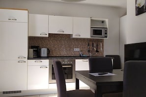 A compact kitchen with white cabinets, a microwave, and a coffee maker. - Holiday apartment with 1 bedroom (Ostseebad Baabe)