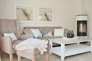 A living room with a beige sofa, a white coffee table, and a fireplace. - Holiday home in Zingst with swimming pool (Zingst)