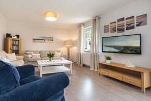 A living room with a sofa, a coffee table, a TV, and a bookshelf. - Holiday home in Zingst with Wi-Fi and parking (Zingst)