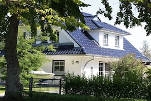 A two-story house with a sloped roof, a visible chimney, and a gated entrance. - Holiday home in Zingst with Wi-Fi and parking (Zingst)
