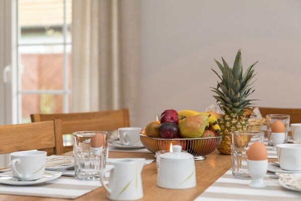 A dining table set with a fruit bowl, cups, glasses, and a teapot. - Holiday home in Zingst with Wi-Fi and parking (Zingst)
