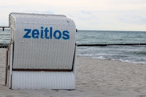 A beach chair with the word 'zeitlos' on it, placed on a sandy beach with the ocean in the background. - Holiday home in Zingst with Wi-Fi and parking (Zingst)