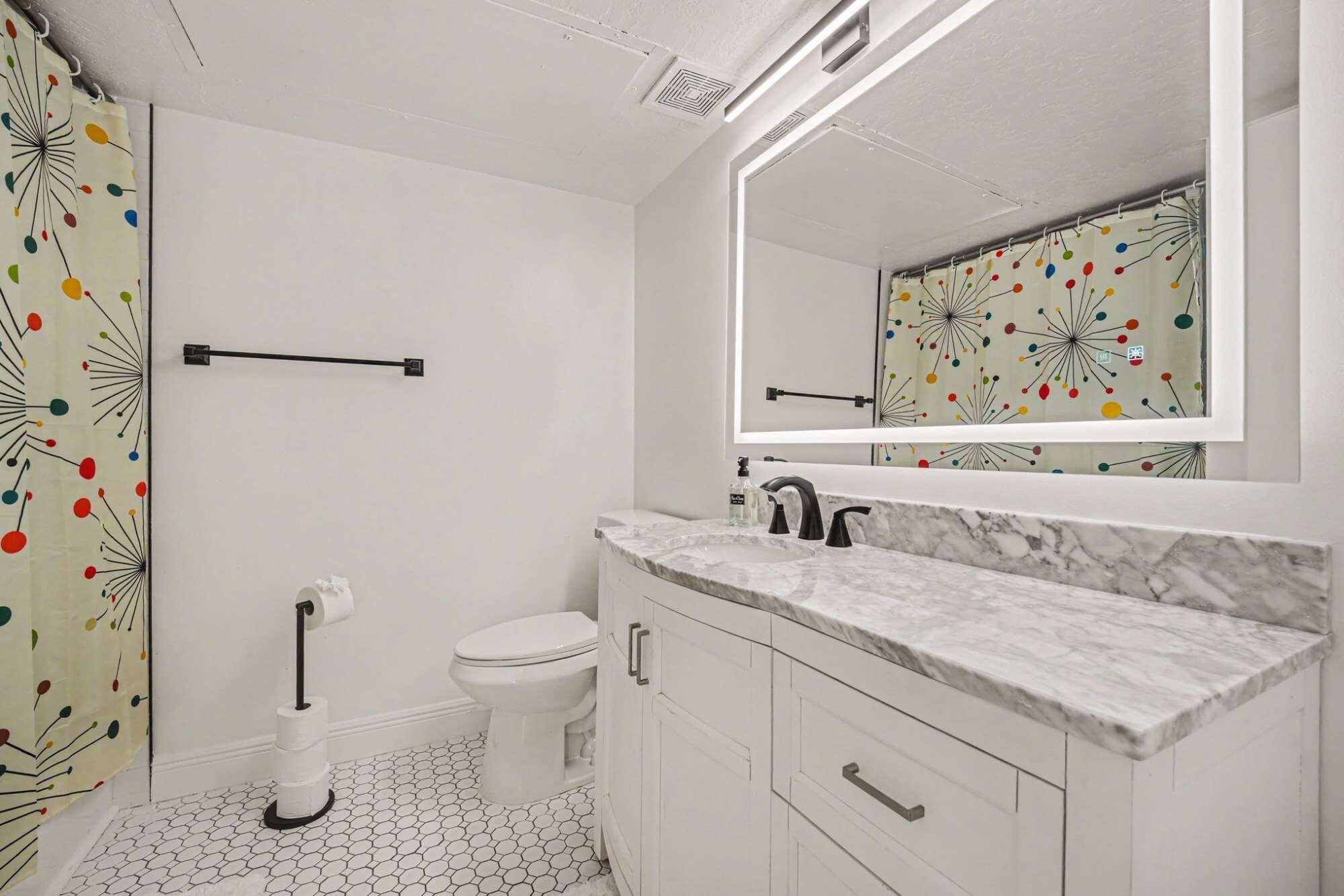 Un baño con inodoro, lavamanos y espejo.