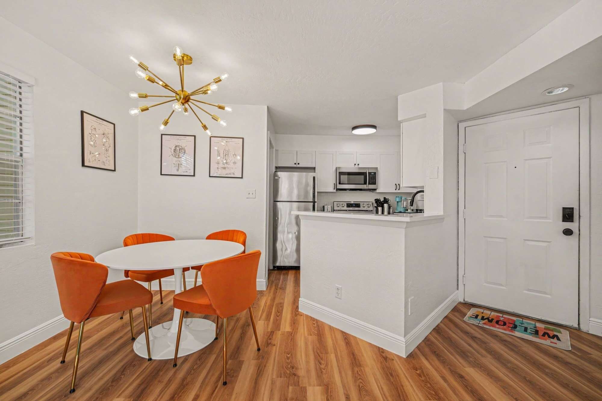A modern kitchen with white cabinets, a stainless steel refrigerator, a microwave, and a coffee machine.