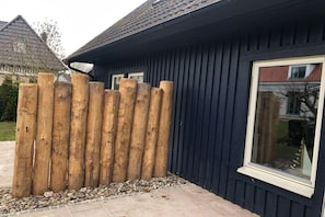 Ein Haus mit dunkler Fassade, einem Holzzaun und einem Fenster.