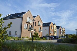 A row of modern residential buildings with balconies, a parking area, and a clear sky. - Holiday apartment with 2 bedrooms (Heiligenhafen)