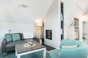 A modern living room with a sofa, a coffee table, a lamp, and a cabinet. - Holiday apartment with 2 bedrooms (Heiligenhafen)