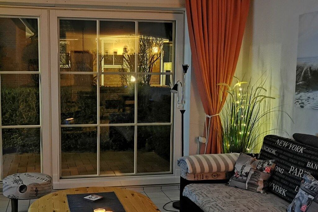 A living room with a sliding glass door, a sofa with patterned cushions, and a small table with a candle.