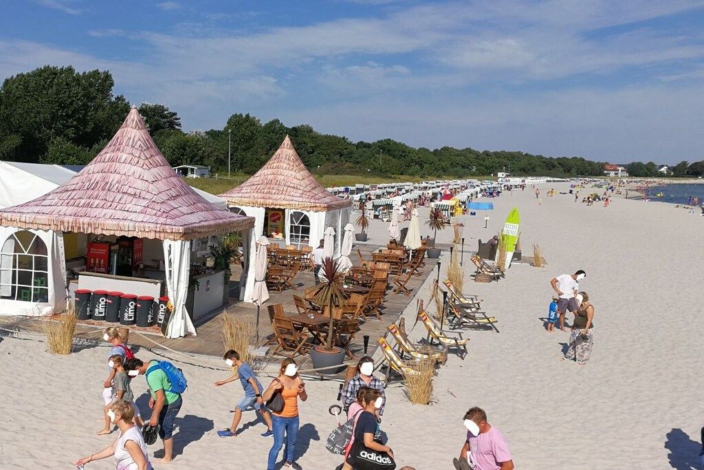A beachside area with beach chairs, umbrellas, and a few people.