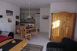 A compact living space with a dining area, kitchenette, and a large wooden wardrobe. - Holiday apartment with 1 bedroom (Boltenhagen-Redewisch)