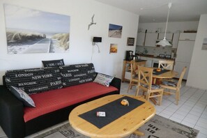 Una sala de estar con sofá, una mesa de centro y un comedor con sillas y una mesa.