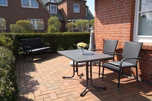 An outdoor patio with a table and chairs, a bench, and a flower arrangement. - Holiday apartment with 1 bedroom (Boltenhagen-Redewisch)