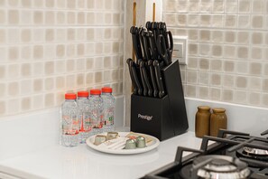 A kitchen counter with a knife block, water bottles, salt and pepper shakers, and a plate with condiments. - Seven Palm | 1BR, Sweet, Stylish & Serene (Dubai)