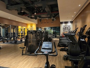 A gym with cardio equipment, weight machines, and a motivational quote on the wall. - Seven Palm | 1BR, Sweet, Stylish & Serene (Dubai)