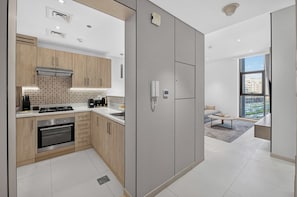 A modern kitchen with a built-in oven, a gas stove, and a large window. - Seven Palm | 1BR, Sweet, Stylish & Serene (Dubai)