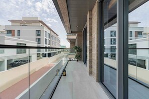 A modern building with large windows, a balcony, and a view of other buildings. - Dere Residences - 108 (Dubai)