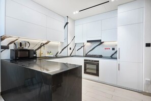 A modern kitchen with a central island, built-in appliances, and a sleek design. - Trillionaire | 1BR, Trendy, Timeless & Tempting (Dubai)