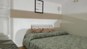 A bedroom with a bed, a wall-mounted shelf with clothes, and a window. - Beach House in Sardinia - 100 meters from the sea, with a garden and barbecue (Quartu Sant'Elena)