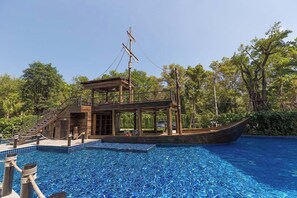 Ein bootsförmiger Pool mit einer Holzterrasse und einem überdachten Sitzbereich.