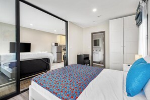 Ein Hotelzimmer mit Bett, Schreibtisch, Spiegel und einer Küchenzeile.