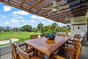 An outdoor dining area with a wooden table and chairs, a ceiling fan, and a view of a golf course. - El Tigre De Luxe, Spacious PH Terrace & Golf View (Nuevo Vallarta)