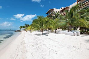 Ein Strandhotel mit weißem Sand, Palmen und blauem Himmel.