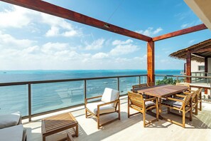 A wooden deck with a table and chairs, overlooking a clear blue sea. - Artila PH: Modern Luxury with Private Terrace and Direct Access to the Beach (Isla Mujeres)