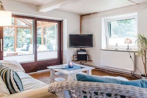 A living room with a sofa, a coffee table, a television, and a window. - Farmhouse by the sea || Langballig (Langballig)